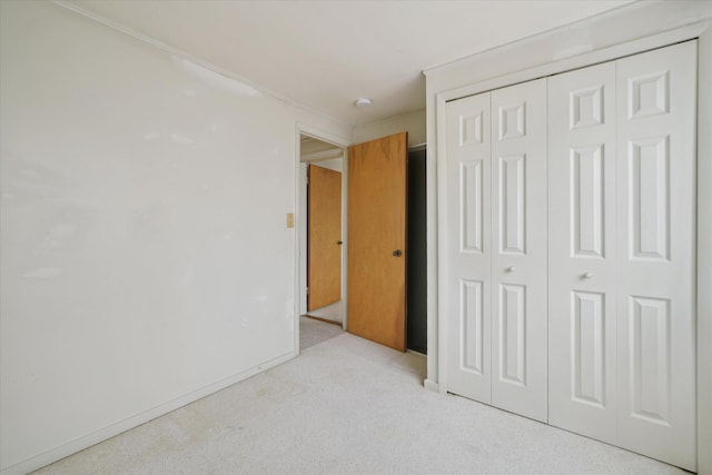 unfurnished bedroom featuring light carpet and a closet