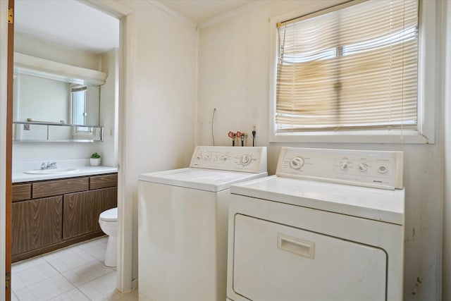 washroom with sink, light tile patterned floors, ornamental molding, and washing machine and clothes dryer