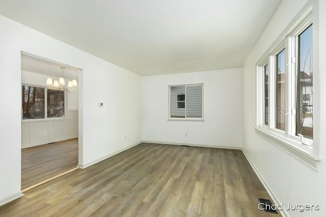 empty room featuring hardwood / wood-style flooring, a healthy amount of sunlight, and a notable chandelier