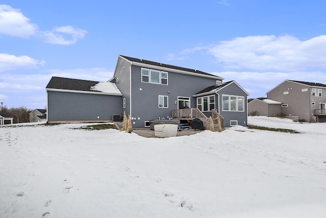 snow covered house with a wooden deck and cooling unit