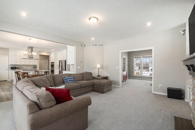 carpeted living room with a textured ceiling and a chandelier