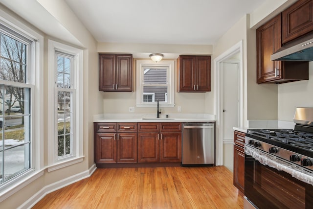 kitchen featuring stainless steel appliances, sink, light hardwood / wood-style flooring, and range hood