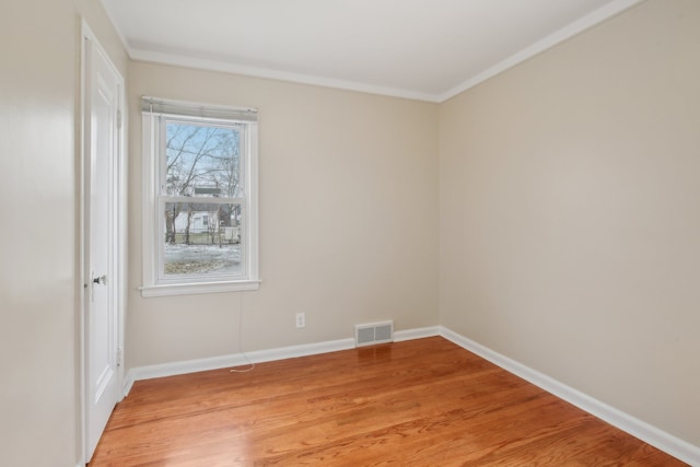 empty room featuring wood-type flooring and crown molding