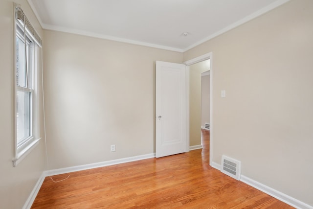 spare room with crown molding, light hardwood / wood-style floors, and a wealth of natural light