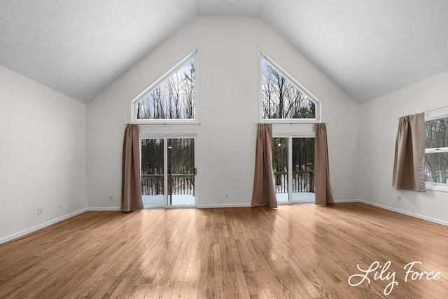 interior space featuring plenty of natural light, high vaulted ceiling, a textured ceiling, and light wood-type flooring