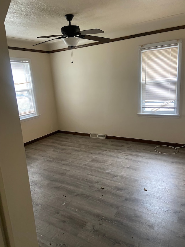 unfurnished room with ceiling fan, wood-type flooring, and a textured ceiling