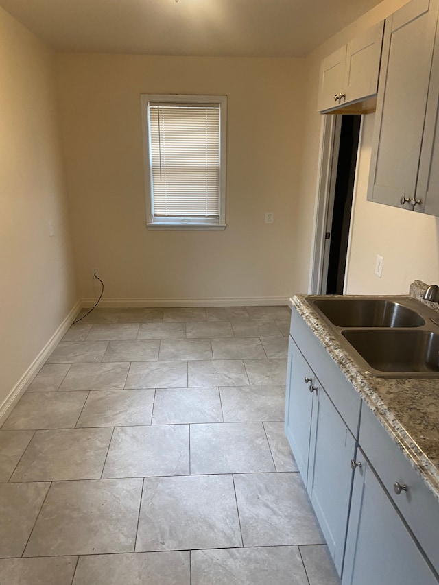 kitchen with stone countertops, sink, and light tile patterned flooring