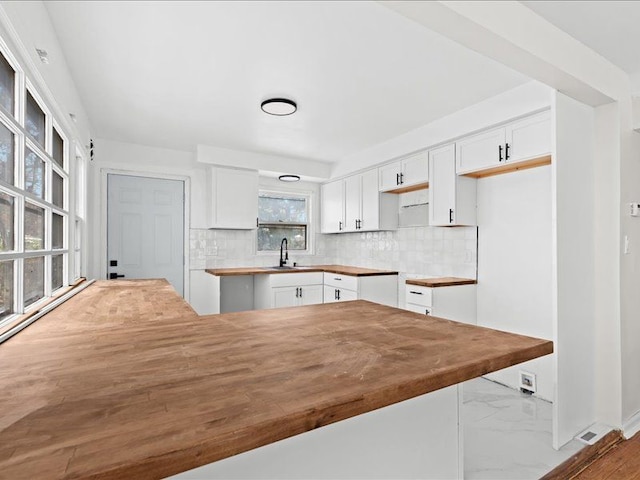 kitchen with backsplash, kitchen peninsula, and white cabinets