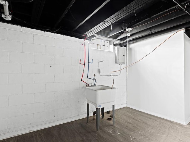 basement with dark hardwood / wood-style floors, sink, and electric panel