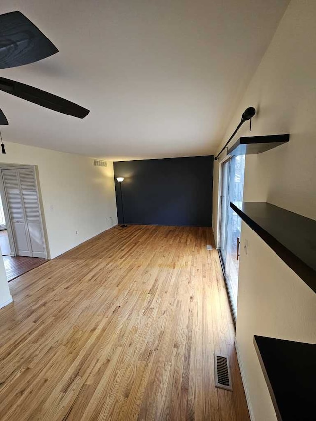 unfurnished living room with ceiling fan, lofted ceiling, and light wood-type flooring