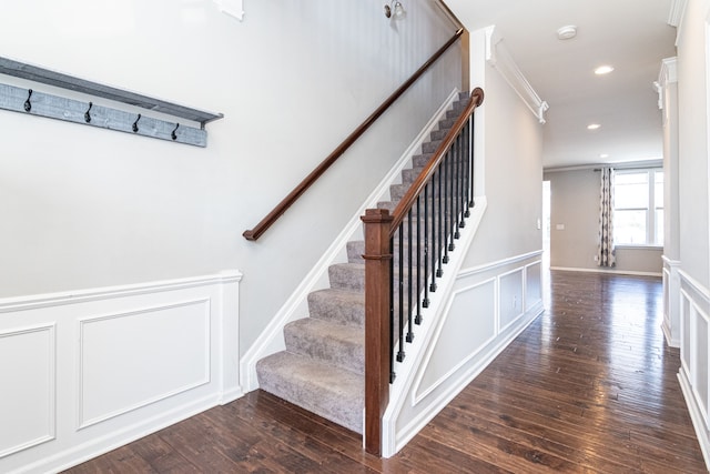 staircase with a decorative wall, recessed lighting, wood finished floors, and wainscoting