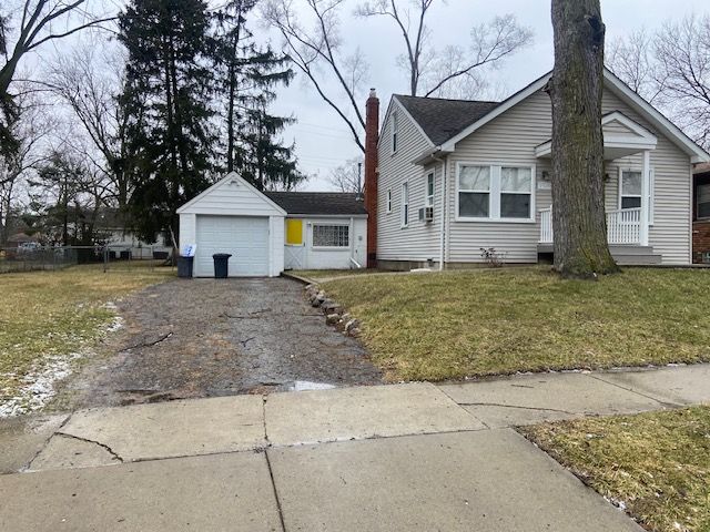 bungalow-style house featuring a garage, covered porch, and a front yard