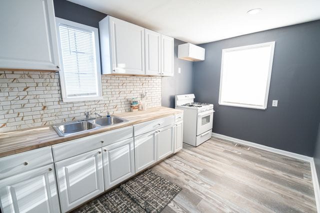 kitchen featuring sink, white gas range, butcher block countertops, and white cabinets