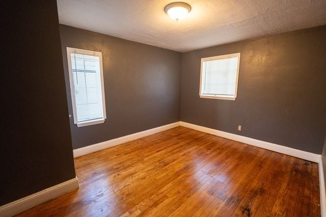 empty room with wood-type flooring and a textured ceiling