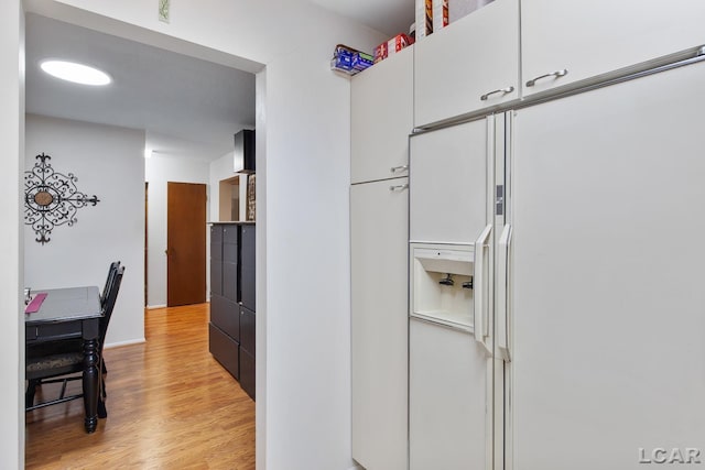 kitchen featuring white cabinets, light hardwood / wood-style flooring, and white fridge with ice dispenser