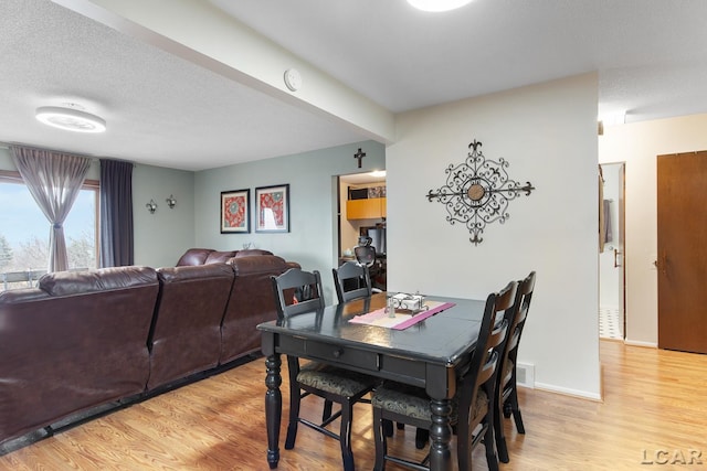 dining space with light hardwood / wood-style floors and a textured ceiling