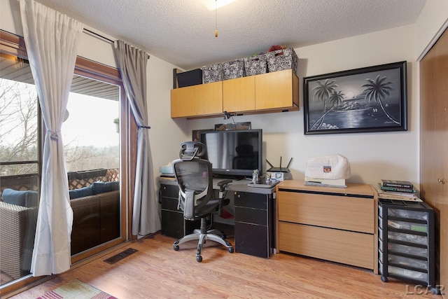 office space featuring wine cooler, light hardwood / wood-style flooring, and a textured ceiling