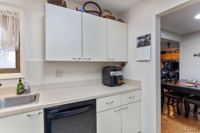 kitchen featuring dishwasher, sink, white cabinets, and light hardwood / wood-style floors