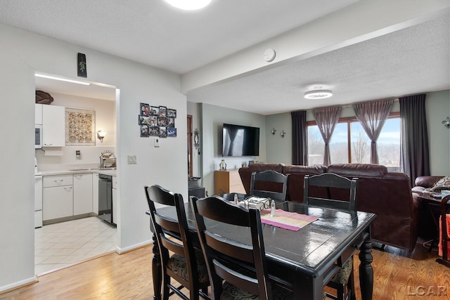 dining area with light hardwood / wood-style flooring and a textured ceiling