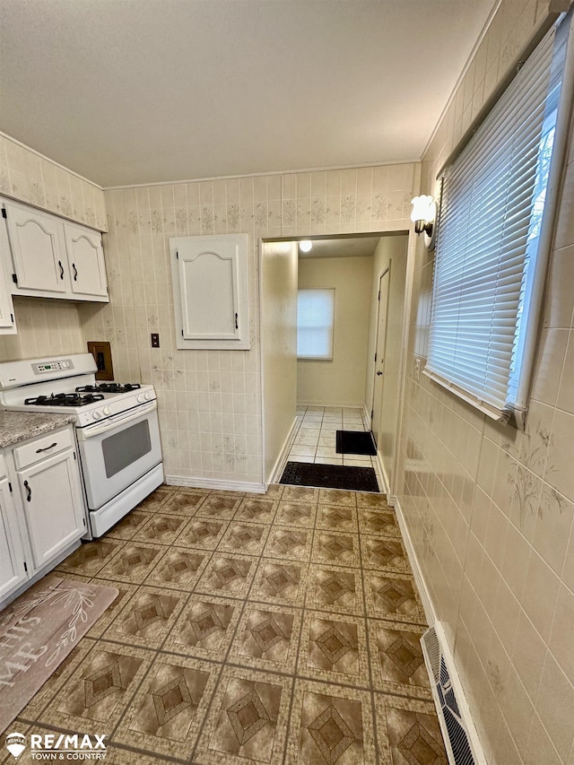 kitchen with white cabinetry, a healthy amount of sunlight, and white range with gas cooktop