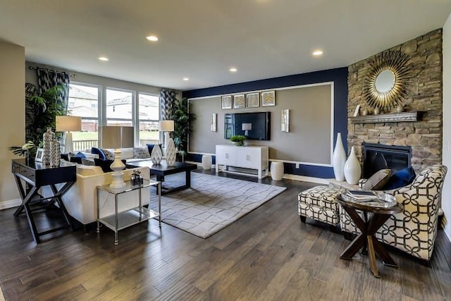 living room with a stone fireplace and dark wood-type flooring