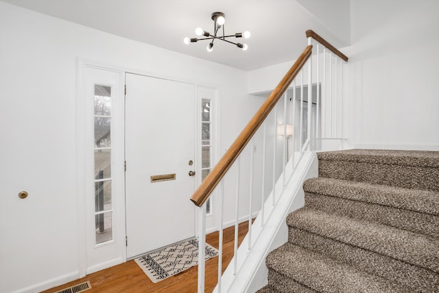 foyer entrance with hardwood / wood-style floors and a chandelier