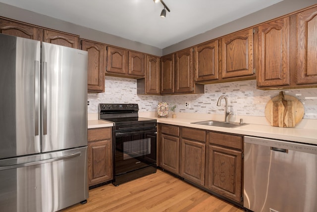 kitchen with sink, backsplash, stainless steel appliances, and light hardwood / wood-style floors