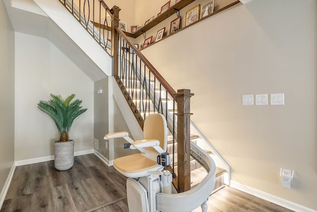 staircase with a towering ceiling and wood-type flooring