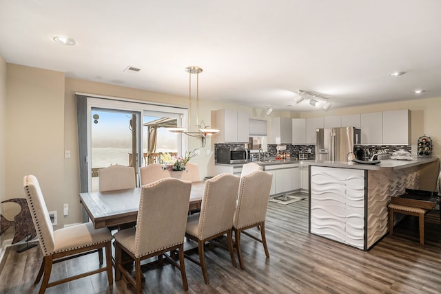 dining room with sink, dark wood-type flooring, and a water view