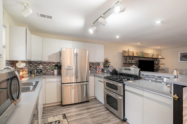 kitchen with white cabinetry, decorative backsplash, light hardwood / wood-style floors, and appliances with stainless steel finishes