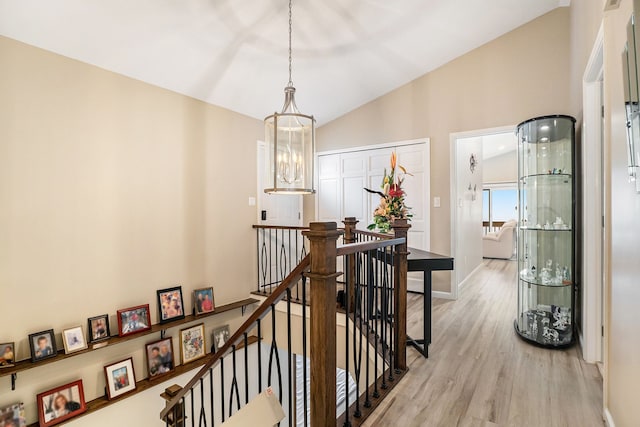 hallway featuring lofted ceiling, light hardwood / wood-style floors, and a chandelier