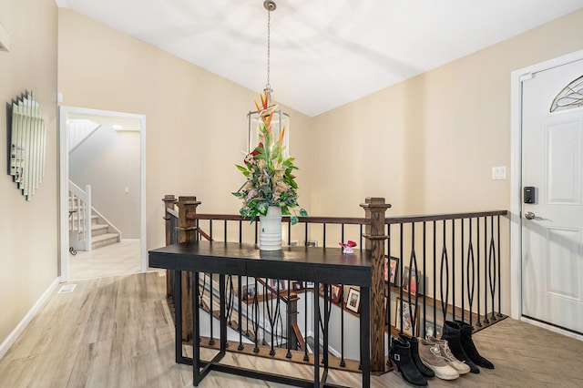 hall with lofted ceiling and light hardwood / wood-style floors