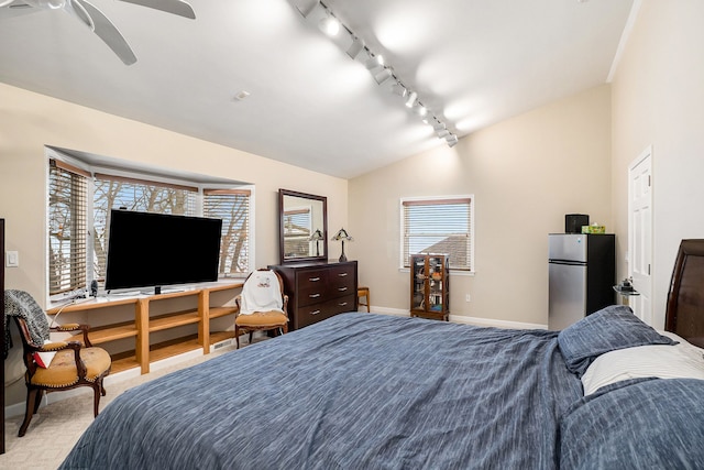 bedroom featuring lofted ceiling, light carpet, track lighting, stainless steel fridge, and ceiling fan