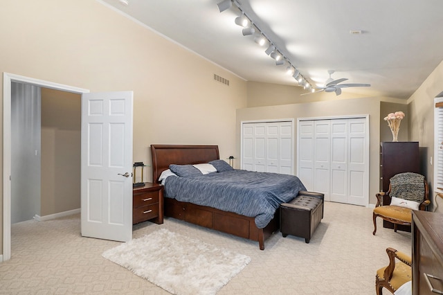 carpeted bedroom featuring multiple closets and lofted ceiling