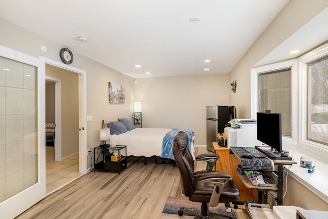 bedroom with stainless steel fridge and light wood-type flooring