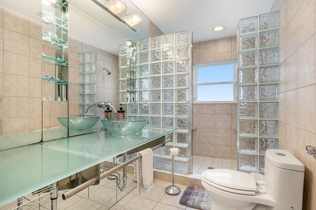 bathroom featuring sink, tile walls, tile patterned flooring, a tile shower, and toilet