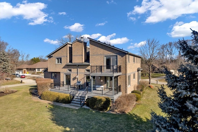 rear view of house with brick siding, a lawn, and a balcony