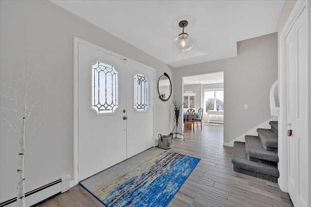 entrance foyer featuring a baseboard heating unit, stairway, and light wood-style flooring