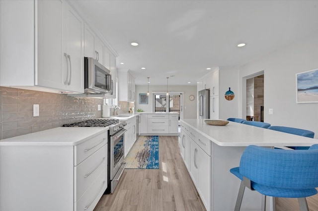 kitchen featuring a kitchen bar, light wood finished floors, high quality appliances, backsplash, and light countertops