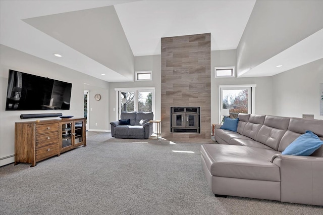 living area featuring carpet flooring, a healthy amount of sunlight, a towering ceiling, and a large fireplace