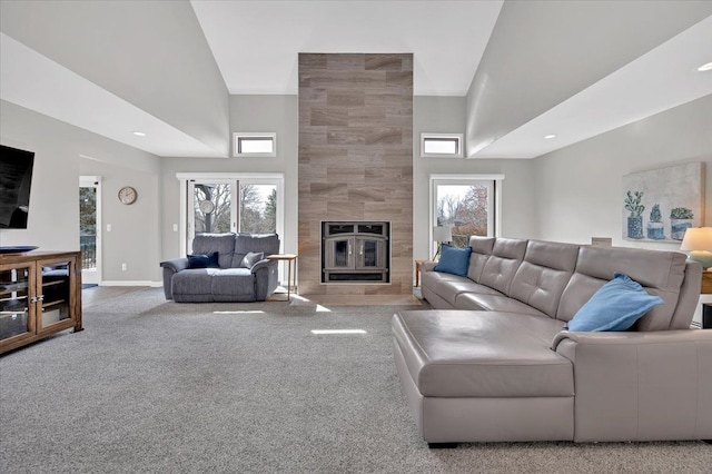 living area with baseboards, carpet floors, a towering ceiling, and a tiled fireplace