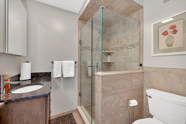 full bath with vanity, visible vents, a stall shower, tile walls, and toilet