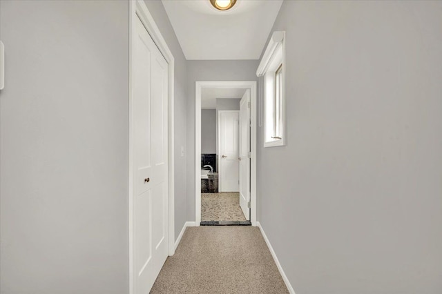 hallway featuring carpet flooring and baseboards