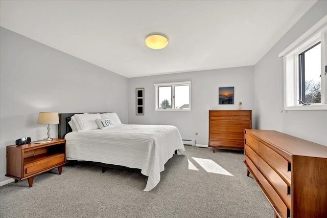 bedroom with a baseboard heating unit, light colored carpet, and baseboards