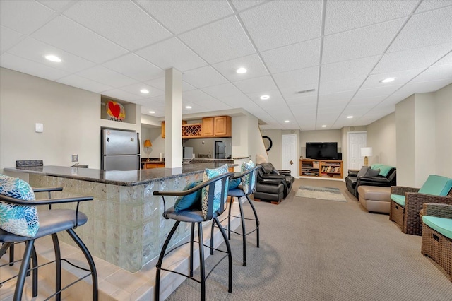 interior space featuring a kitchen breakfast bar, recessed lighting, light colored carpet, and freestanding refrigerator