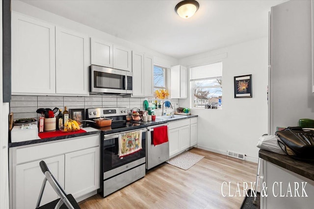 kitchen with backsplash, appliances with stainless steel finishes, sink, and white cabinets