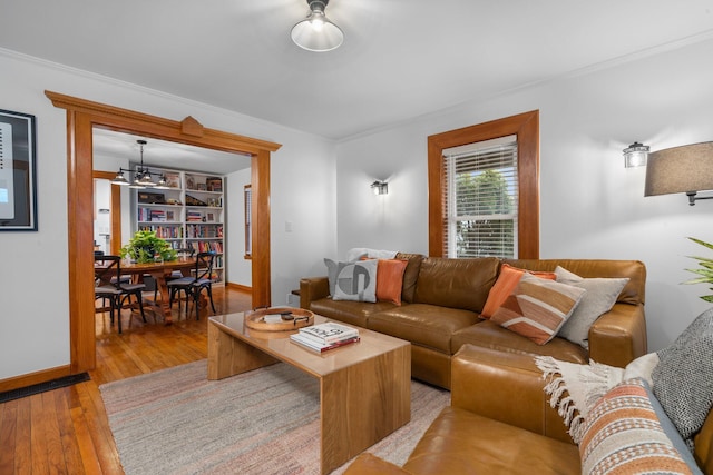 living room with built in features, wood-type flooring, and ornamental molding