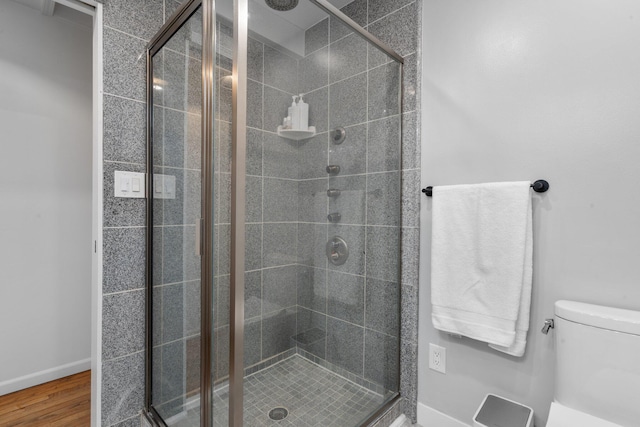 bathroom with wood-type flooring, toilet, and a shower with shower door