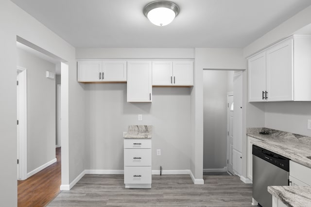 kitchen with stainless steel dishwasher, white cabinets, light stone counters, and light hardwood / wood-style floors