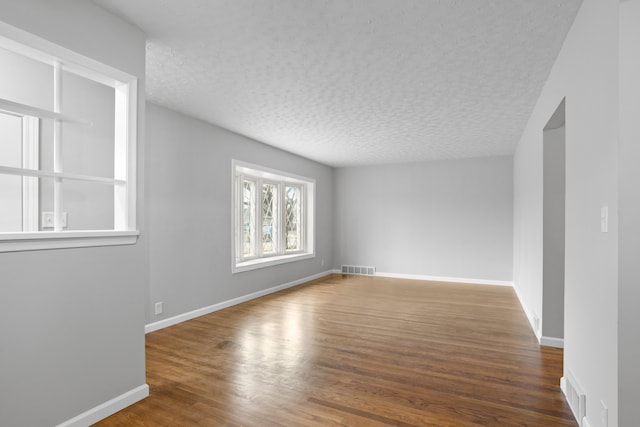 empty room featuring dark hardwood / wood-style flooring and a textured ceiling